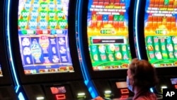 ແມ່ຍິງຄົນນຶ່ງກຳລັງນັ່ງຫຼິ້ນ slot machine ທີ່ໃຊ້ເງິນຫລຽນປ່ອນ ຫຼິ້ນ ຢູ່ Golden Nugget casino ໃນເມືອງ Atlantic City ລັດນິວເຈີຊີ ວັນທີ 2 ກໍລະກົດ 2020.