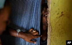 FILE - A 15-year-old girl who was raped when she was 14 talks to a member of UNICEF staff, left, at her home in a village near Masaka, Uganda, June 1, 2017.