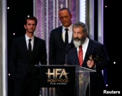 Director Mel Gibson accepts the Hollywood Director Award for "Hacksaw Ridge" as cast members Andrew Garfield, left, and Vince Vaughn look on at the Hollywood Film Awards in Beverly Hills, Calif., Nov. 6, 2016.