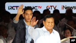 Presidential candidate Prabowo Subianto, right, and his running mate Gibran Rakabuming Raka who is also the eldest son of Indonesian President Joko Widodo, wave at supporters upon arrival to attend a televised presidential candidates' debate in Jakarta, Indonesia, Jan. 7, 2024. 