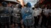 Un policía antimotines es bañado con tinta azul por manifestantes cerca del edificio del Congreso después que manifestantes incendiaron parte del edificio en Ciudad de Guatemala, el sábado 21 de noviembre de 2020.