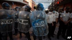 Un policía antimotines es bañado con tinta azul por manifestantes cerca del edificio del Congreso después que manifestantes incendiaron parte del edificio en Ciudad de Guatemala, el sábado 21 de noviembre de 2020.