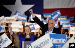 Democratic presidential candidate Sen. Bernie Sanders, I-Vt., right, with his wife Jane, raises his hand as he speaks during a campaign event in San Antonio, Feb. 22, 2020.
