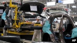 FILE - A worker prepares to put a spare tire into a Haval SUV H2 model in the Great Wall Motors assembly plant in Baoding in north China's Hebei province, Feb. 19, 2017.