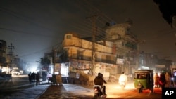 Vehicles headlights light a dark street during widespread power outages in Rawalpindi, Pakistan, Jan. 10, 2021. 