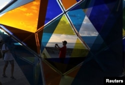 People stand next to an installation by Spanish artist David Magan on the Malecon, during the 13th Havana Biennial, in Havana, Cuba, April 13, 2019.