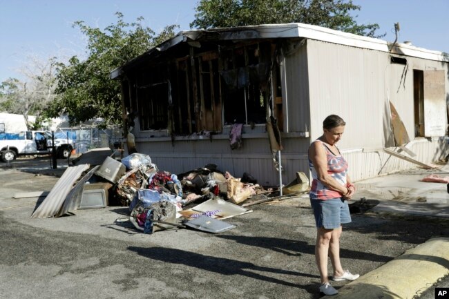 Katherine Johnson-Coates afuera de la casa móvil incendiada de un vecino después de un terremoto el sábado 6 de julio de 2019, en Ridgecrest, California.