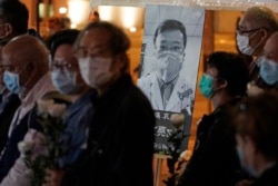 People wearing masks, attend a vigil for Chinese doctor Li Wenliang, in Hong Kong, Feb. 7, 2020.