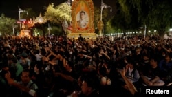 FILE - Pro-democracy demonstrators stand in front of a portrait of Thailand's King Maha Vajiralongkorn outside the Government House during an anti-government mass protest, on the 47th anniversary of the 1973 student uprising, in Bangkok, Thailand, Oct. 14