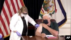 FILE - A nurse administers a coronavirus shot to west Virginia Gov. Jim Justice, Dec. 14, 2020, in Charleston, W.Va.