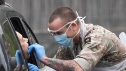 Un miembro del ejército prueba a una persona en un centro de pruebas de coronavirus en el estacionamiento de Chessington World of Adventures, en Washington.