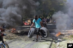 A resident carries tires to be added to a burning barricade to deter gang members from entering his neighborhood, in Port-au-Prince, Haiti, Nov. 19, 2024.