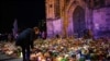 A woman bends to place a tribute with flowers and candles left near the 'Alter Markt' Christmas market, where a man drove a car into the crowd through an emergency exit route on Friday evening, in Magdeburg, Germany, Dec. 22, 2024. 