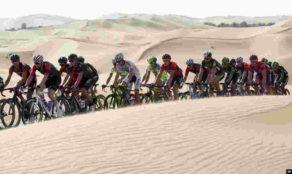 The pack pedals along desert dunes, during the first stage of the Abu Dhabi tour cycling race, from Qasr Al Sarab to Madinat Zayed, UAE.