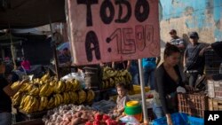 FILE - A boy sits on a vegetable stand while accompanying his mother at a street market in Caracas, Venezuela, Oct. 27, 2017. The sign reads in Spanish 'Everything for 1500.'