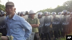 Villagers stand next to riot police deployed to Vietnam's northern Hung Yen province during a protest on April 24, 2012. Local residents tried block police from taking control of a disputed plot of land outside Hanoi in the second high-profile clash over 