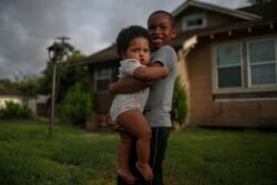 Vincent Turner, 6, holds his eight-month-old sister Faith while playing in the front yard of their home ahead of the arrival of Hurricane Laura in Beaumont, Texas, U.S., August 26, 2020. REUTERS/Adrees Latif