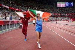 Gold medalists Mutaz Barshim, left, of Qatar and Gianmarco Tamberi of Italy celebrate on the track after the final of the men's high jump at the 2020 Summer Olympics in Tokyo, Aug. 1, 2021.