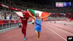 Gold medalists Mutaz Barshim, left, of Qatar and Gianmarco Tamberi of Italy celebrate on the track after the final of the men's high jump at the 2020 Summer Olympics in Tokyo, Aug. 1, 2021.