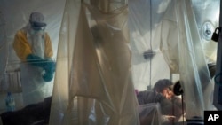 FILE - Health workers wearing protective gear check on a patient isolated in a plastic cube at an Ebola treatment center in Beni, Congo, July 13, 2019. 