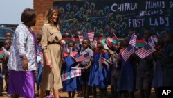 First lady Melania Trump is escorted by head teacher Maureen Masi as she arrives for a visits Chipala Primary School, in Lilongwe, Malawi, Oct. 4, 2018. 