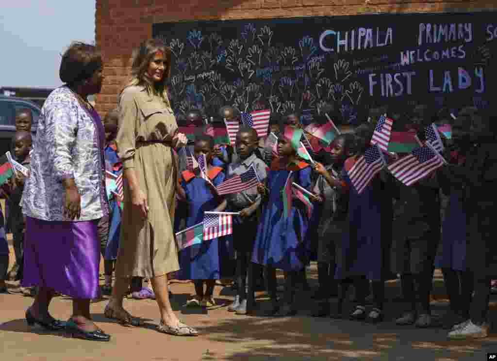 First lady Melania Trump is escorted by head teacher Maureen Masi as she arrives for a visits Chipala Primary School, in Lilongwe, Malawi, Oct. 4, 2018. 