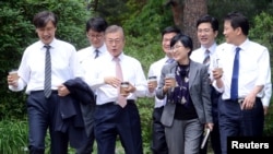 South Korean President Moon Jae-in takes a walk with senior presidential secretaries at the Presidential Blue House in Seoul, South Korea, May 11, 2017.