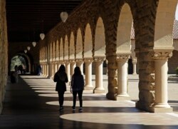 FILE- In this March 14, 2019, file photo students walk on the Stanford University campus in Santa Clara, Calif.