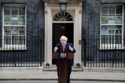 British Prime Minister Boris Johnson makes a statement flanked by children's drawings of rainbows supporting the National Health Service (NHS) displayed in windows, on his first day back at work in Downing Street, London, April 27, 2020.