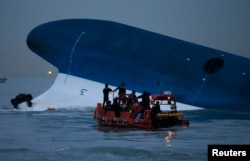 FILE - Maritime police search for missing passengers in front of the South Korean ferry Sewol, which sank at the sea off Jindo April 16, 2014.