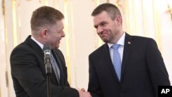 Outgoing Slovakian Prime Minister Robert Fico, left, shakes hands with Peter Pellegrini, who will replace Fico as prime minister, at the Presidential palace in Bratislava, March 15, 2018.