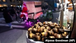 Chestnuts are displayed at a food vendor as a person dressed as Santa Claus offers rides, Thursday, Dec. 12, 2024, in New York. (AP Photo/Alyssa Goodman)