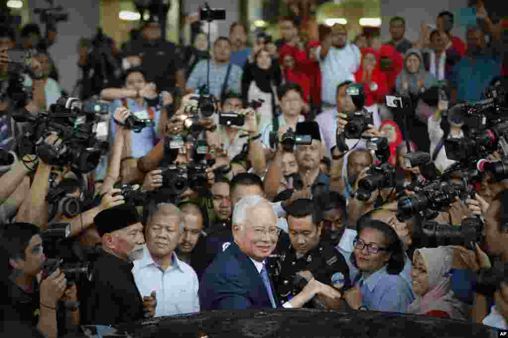 Former Malaysian Prime Minister Najib Razak, center, gets into a car after his court appearance at the Kuala Lumpur High Court. Najib appeared in court for the start of his corruption trial, exactly 10 years after he was first elected to office only to suffer a spectacular defeat last year on allegations he pilfered millions of dollars from a state investment fund.