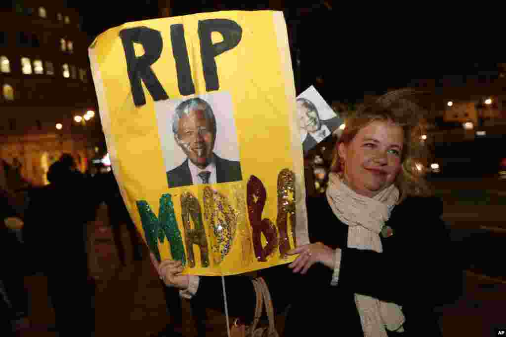 A woman with a banner pays tribute to Nelson Mandela outside the South African High Commission in London, Dec. 6, 2013.