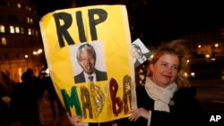 A woman with a banner pays tribute to Nelson Mandela outside the South African High Commission in London, Dec. 6, 2013.