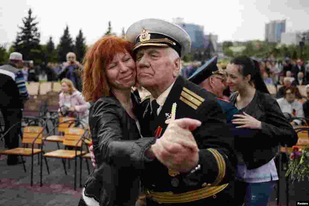 A woman dances with a veteran near the Defenders of Donbass monument during celebrations to mark Victory Day in Donetsk, eastern Ukraine May 9, 2014.