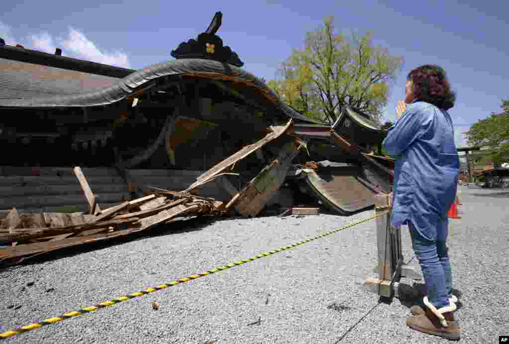 A woman prays in front of the historic Aso Shrine collapsed by powerful earthquakes in Aso, Kumamoto prefecture, April 17, 2016.