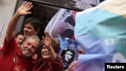 FILE - Brazil's President and Workers' Party (PT) presidential candidate Dilma Rousseff (R) and her predecessor Luiz Inacio Lula da Silva wave to supporters during a campaign rally in Sao Paulo, Oct. 3, 2014. 