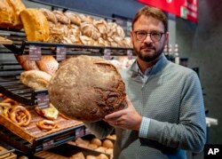 Baker Andreas Schmitt shows a loaf of bread in the Cafe Ernst bakery, in Neu Isenburg, Germany, Monday, Sept. 19, 2022. Schmitt is heating fewer ovens at his 25 Ernst Cafe bakeries, running them longer to spare startup energy, narrowing his pastry selection to ensure ovens run full, and storing less dough to cut refrigeration costs. (AP Photo/Michael Probst)