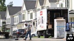 Un trabajador barre la calle frente a una hilera de casas nuevas en Fairfax, Virginia, el 22 de agosto de 2023, los economistas prestan gran atención a este sector como indicador clave del comportamiento de la economía.