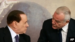 Italian Premier Silvio Berluconi, left, and Vice Premier Gianni Letta share a word during a press conference at the end of a Cabinet Ministers meeting on the approval of the new austerity measures, in Rome, Aug. 12, 2011