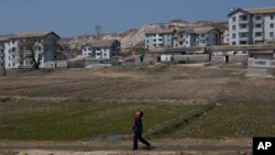 Seorang warga Korea Utara berjalan di depan jalanan desa industri Kaesong, Korea Utara (24/4). Korut telah menolak usul Korsel terkait nasib kawasan industri bersama ini, meskipun telah melewati batas waktu yag ditetapkan Korsel, Jumat (26/4).