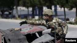 FILE - A U.S. soldier inspects the site of a suicide bomb attack in Kabul, Afghanistan, June 30, 2015.