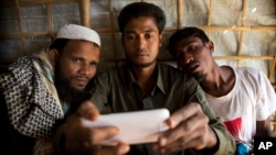 Rohingya Muslim refugee Mohammad Karim, 26, center, shows a mobile video of Gu Dar Pyin's massacre to other refugees in Kutupalong refugee camp, Bangladesh, Jan. 14, 2018.