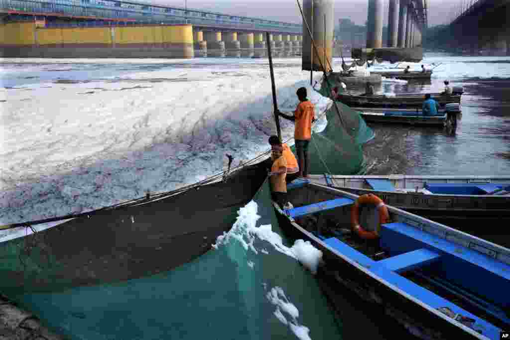 Workers for the Delhi Jal or water board put up a cloth curtain to stop the flow of the toxic foams floating in the river Yamuna in New Delhi, India.