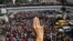 A demonstrator shows the three-finger salute as people rally in a protest against the military coup and to demand the release of elected leader Aung San Suu Kyi, in Yangon, Myanmar, Feb. 7, 2021.