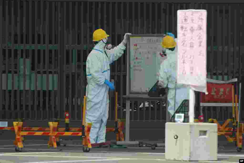 Guards read a whiteboard near the Fukushima-1 nuclear plant's main gate, April 13, 2011 (VOA Photo S. Herman)
