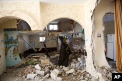 A Palestinian woman inspects the home of Ehab Maswada that was demolished by the Israeli army in the West Bank city of Hebron, March 31, 2016.