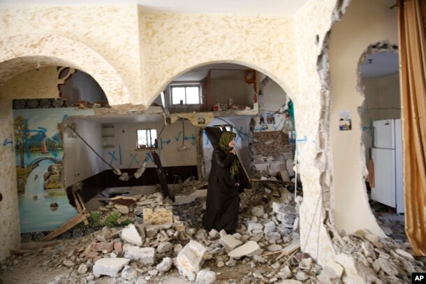 Palestinian woman inspects the home of Ehab Maswada that was demolished by the Israeli army in the West Bank city of Hebron, Thursday, March 31, 2016.