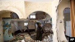 Palestinian woman inspects the home of Ehab Maswada that was demolished by the Israeli army in the West Bank city of Hebron, Thursday, March 31, 2016.